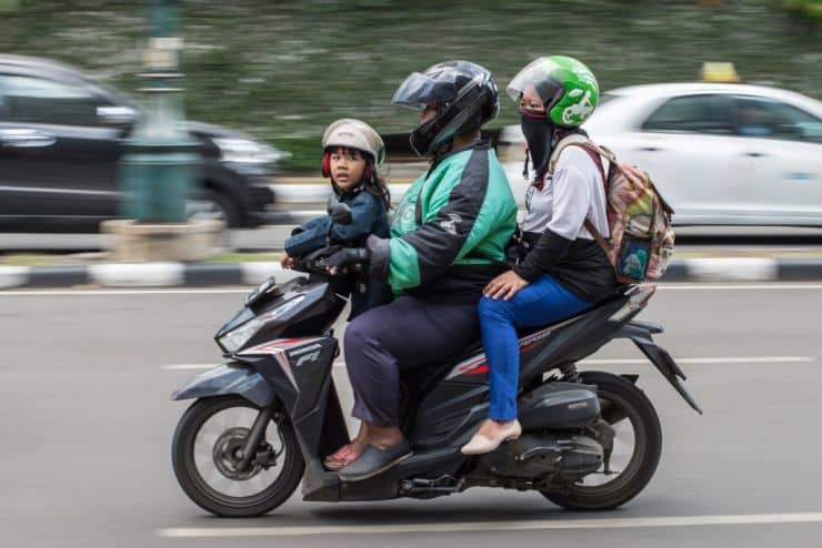 Three People Sitting on a Scooter